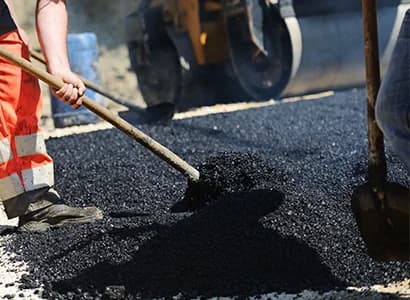 Road crew spreading fresh bitumen