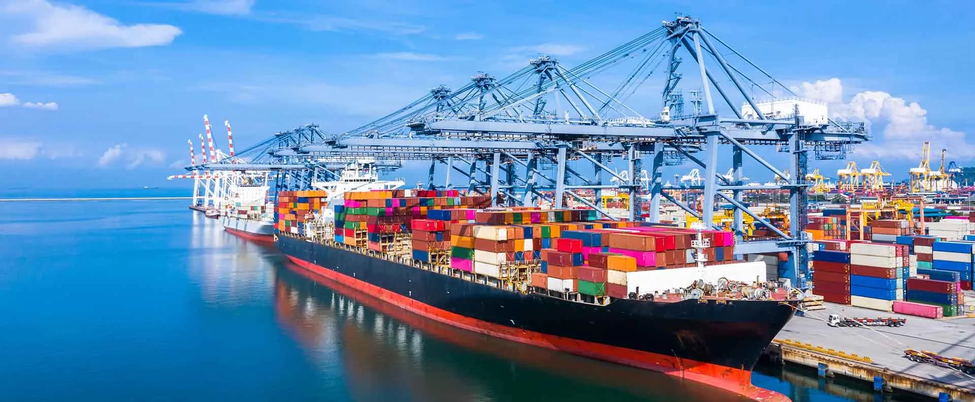 A container vessel alongside a quay under gantry cranes.