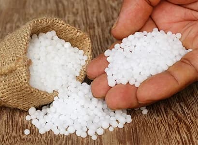 White urea prills held in an open hand over a sack